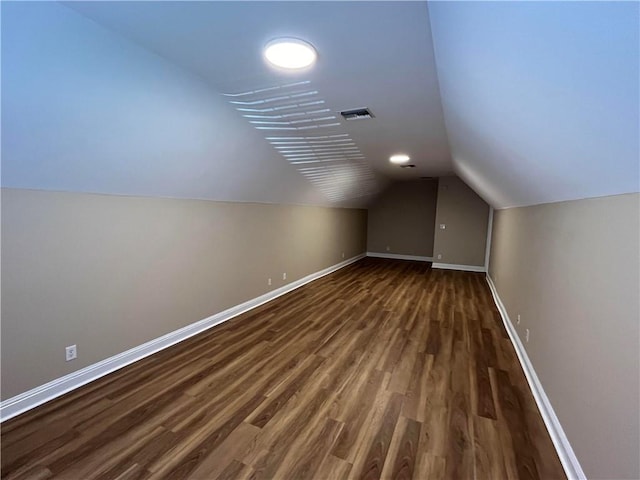 additional living space with vaulted ceiling and dark hardwood / wood-style floors