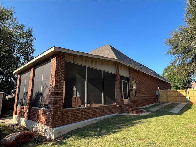 view of side of property featuring a sunroom and a lawn