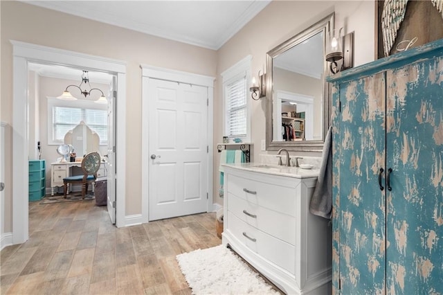 bathroom with a healthy amount of sunlight, vanity, wood-type flooring, and ornamental molding