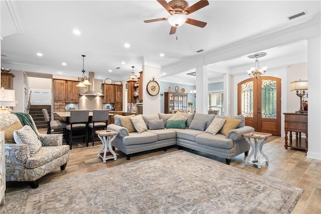 living room featuring ceiling fan with notable chandelier, light wood-type flooring, and ornamental molding