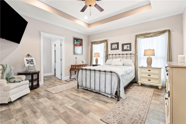 bedroom featuring light wood-type flooring, crown molding, ceiling fan, and a raised ceiling