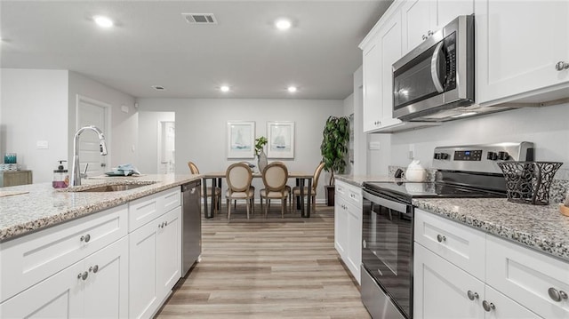10570 Relic Rd S, Mobile, AL 36608 - kitchen featuring stainless steel appliances, light wood-style floors, recessed lighting, white cabinetry, and light stone counters