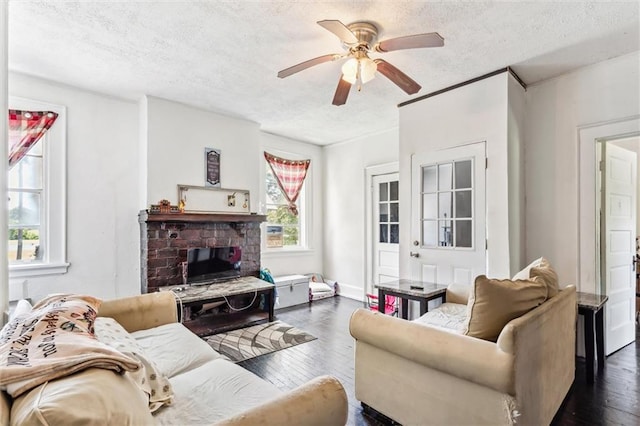 living room with dark wood-type flooring, ceiling fan, a textured ceiling, and a fireplace