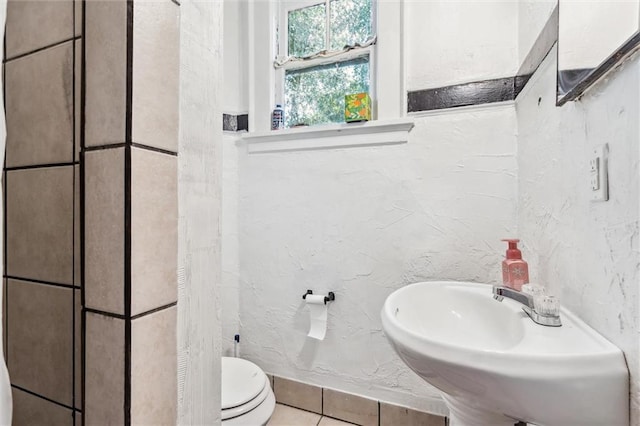 bathroom with toilet, tile patterned floors, and sink