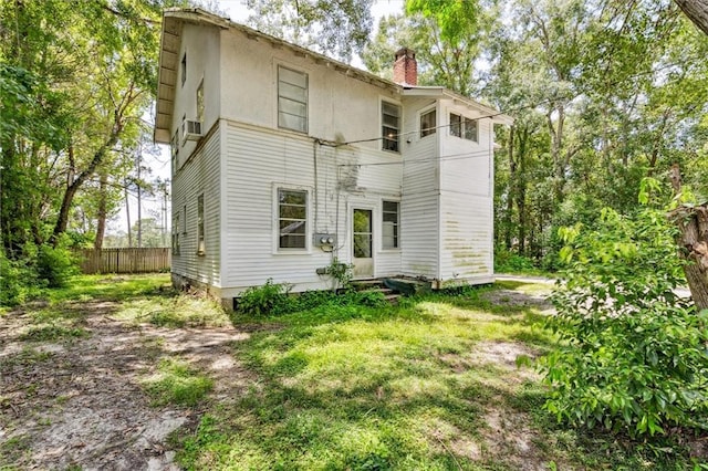 back of property featuring a balcony and a lawn