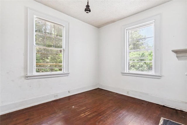 unfurnished room featuring dark wood-type flooring, a textured ceiling, and plenty of natural light