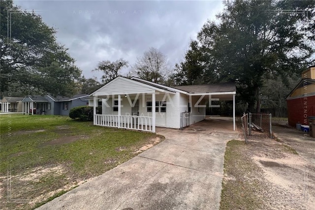 view of front of house featuring covered porch, a front yard, and a carport