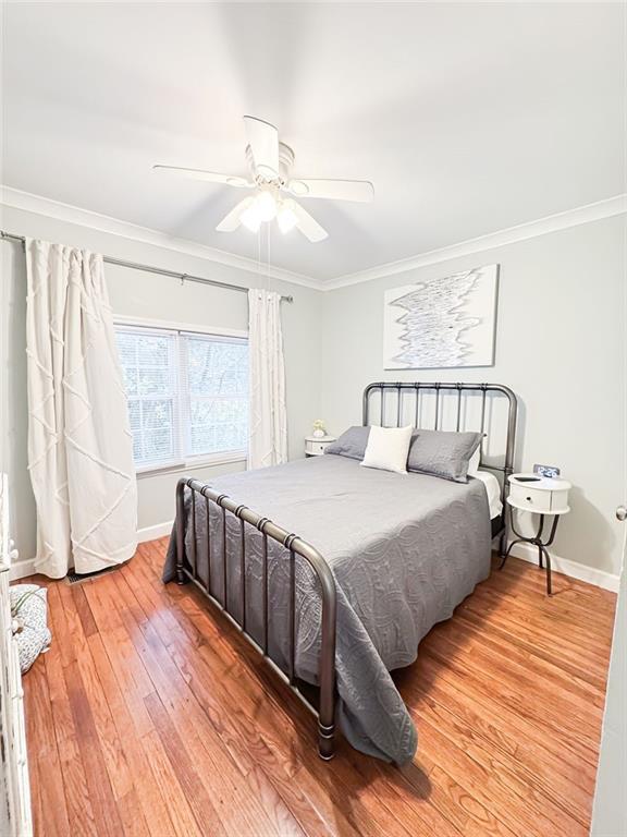 bedroom featuring baseboards, ceiling fan, crown molding, and light wood finished floors