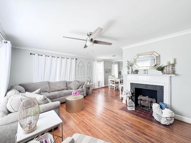 living area with baseboards, wood finished floors, ceiling fan, and ornamental molding