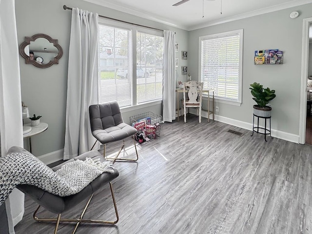 living area with baseboards, ornamental molding, visible vents, and wood finished floors