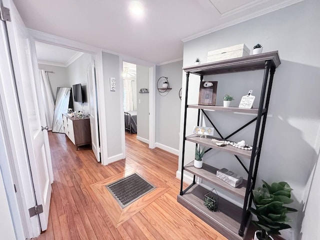 hallway featuring ornamental molding, baseboards, light wood finished floors, and visible vents