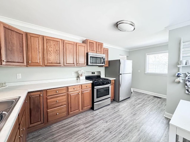 kitchen featuring ornamental molding, light wood-style flooring, brown cabinetry, and appliances with stainless steel finishes