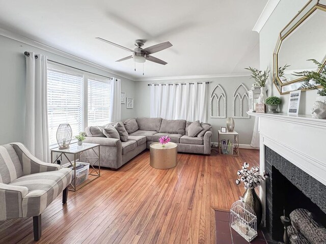 living room with a fireplace with flush hearth, crown molding, hardwood / wood-style flooring, baseboards, and ceiling fan