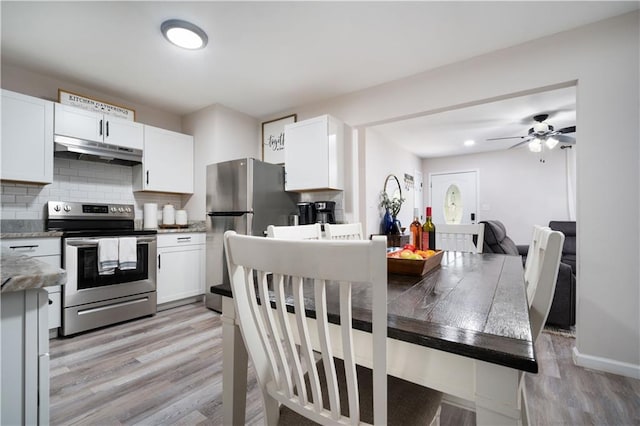 kitchen featuring under cabinet range hood, white cabinets, stainless steel appliances, and tasteful backsplash
