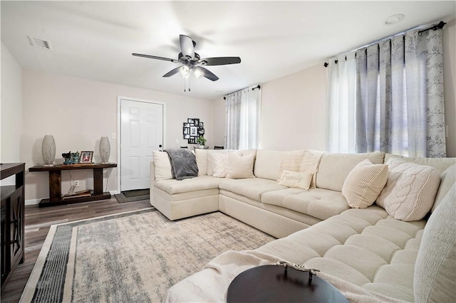 living area featuring visible vents, wood finished floors, baseboards, and ceiling fan