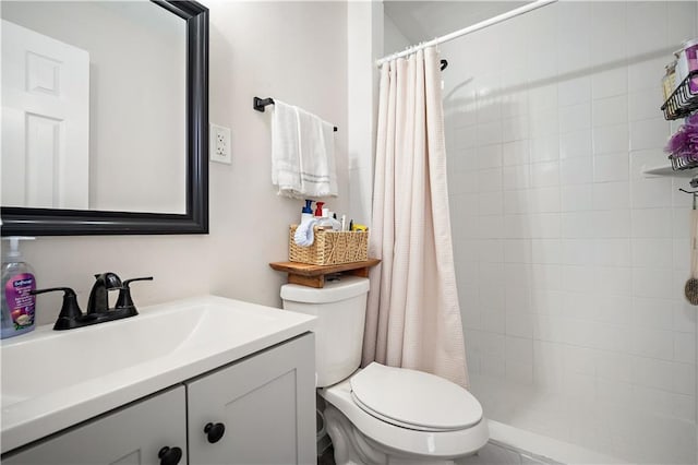 bathroom featuring vanity, toilet, and tiled shower