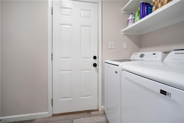 clothes washing area with light wood-type flooring, baseboards, independent washer and dryer, and laundry area
