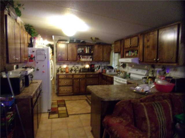 kitchen featuring kitchen peninsula, white appliances, lofted ceiling, and light tile patterned floors