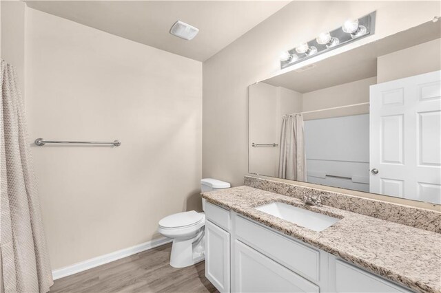 bathroom with toilet, vanity, and wood-type flooring