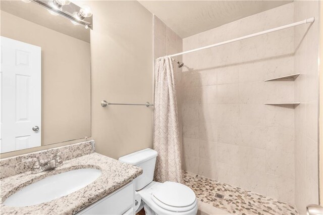 bathroom featuring vanity, walk in shower, and toilet