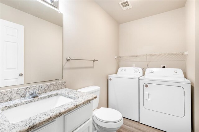 bathroom with washing machine and dryer, wood-type flooring, toilet, and vanity