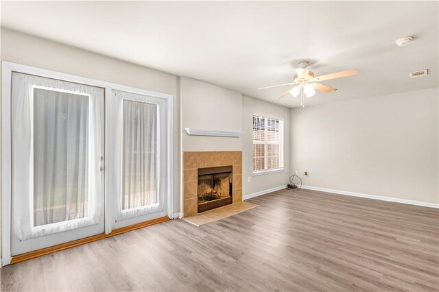 unfurnished living room featuring a wealth of natural light, light wood-type flooring, and a fireplace