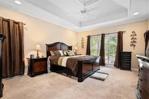 carpeted bedroom with ceiling fan, access to exterior, and a tray ceiling