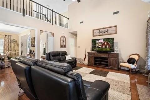 living room with a towering ceiling, ceiling fan, and dark wood-type flooring