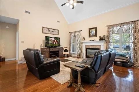 living room with a tiled fireplace, ceiling fan, high vaulted ceiling, and wood-type flooring