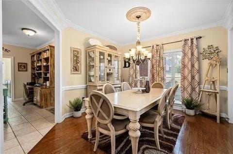 tiled dining space featuring crown molding and a chandelier