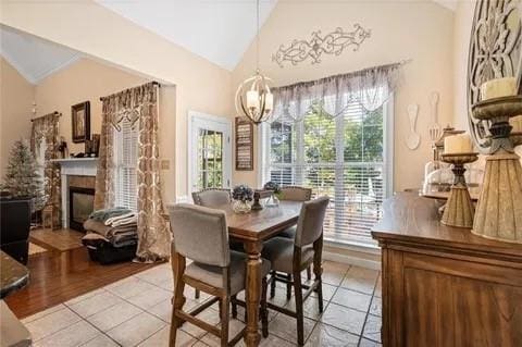 tiled dining room with high vaulted ceiling, a tile fireplace, and a chandelier