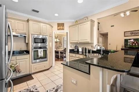 kitchen featuring stainless steel appliances, sink, ceiling fan, light tile patterned floors, and kitchen peninsula