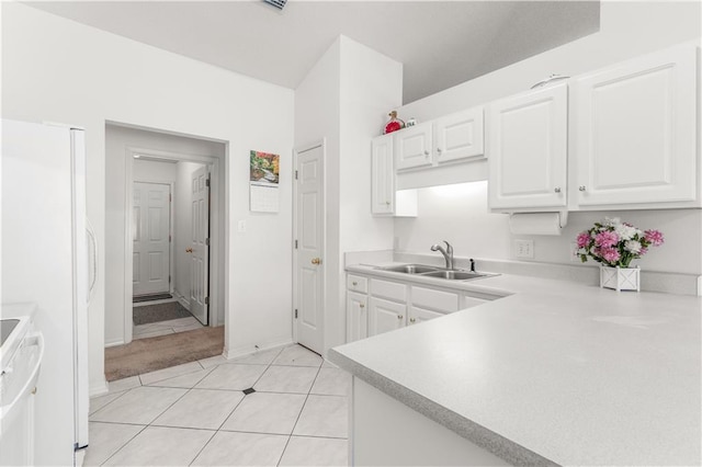 kitchen featuring white cabinets, white refrigerator, sink, light tile patterned flooring, and stove