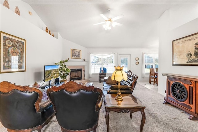 carpeted living room featuring ceiling fan, lofted ceiling, and a tiled fireplace