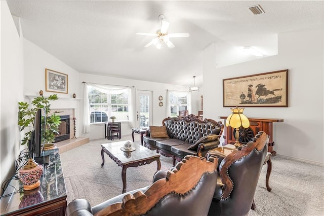 carpeted living room featuring ceiling fan, lofted ceiling, and a tiled fireplace