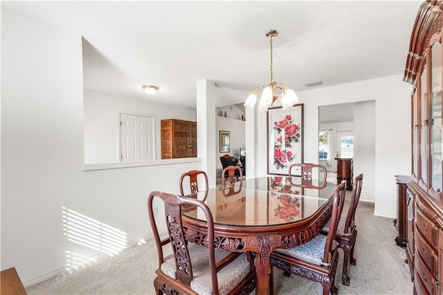 carpeted dining area with an inviting chandelier