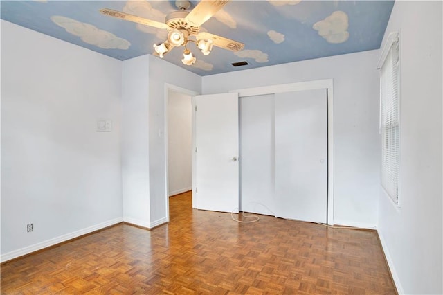 unfurnished bedroom featuring parquet flooring, ceiling fan, and a closet