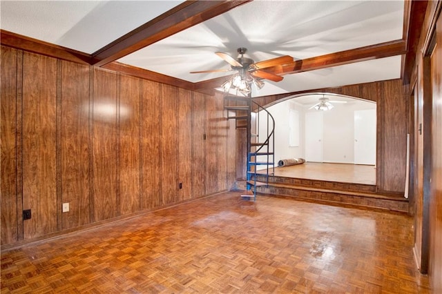 empty room featuring lofted ceiling with beams, parquet flooring, wooden walls, and ceiling fan