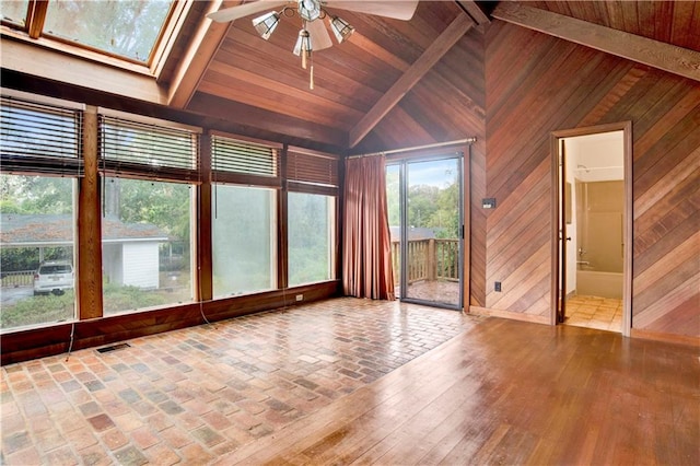 unfurnished sunroom featuring wooden ceiling, vaulted ceiling with skylight, and ceiling fan