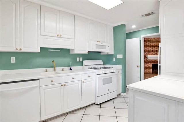 kitchen featuring a brick fireplace, sink, light tile patterned flooring, white cabinetry, and white appliances