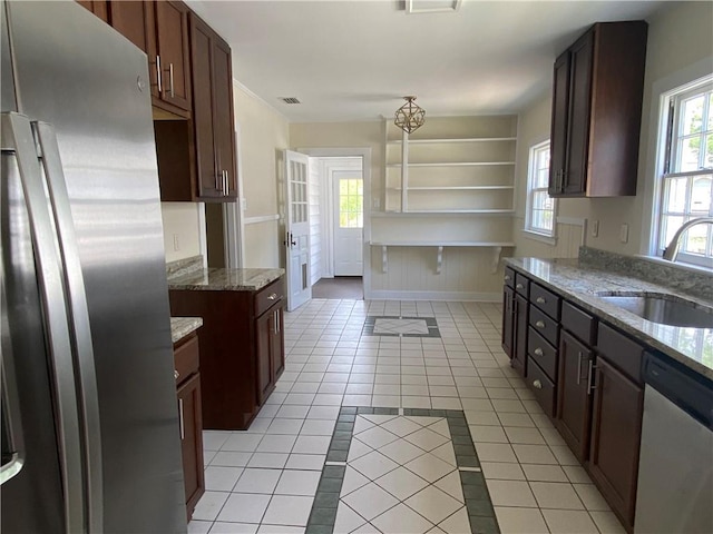 kitchen with light stone counters, hanging light fixtures, appliances with stainless steel finishes, sink, and light tile floors