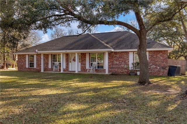 ranch-style home with a shingled roof, a front yard, brick siding, and fence