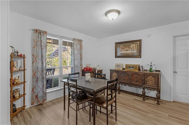 dining space with light wood finished floors, baseboards, and a textured ceiling