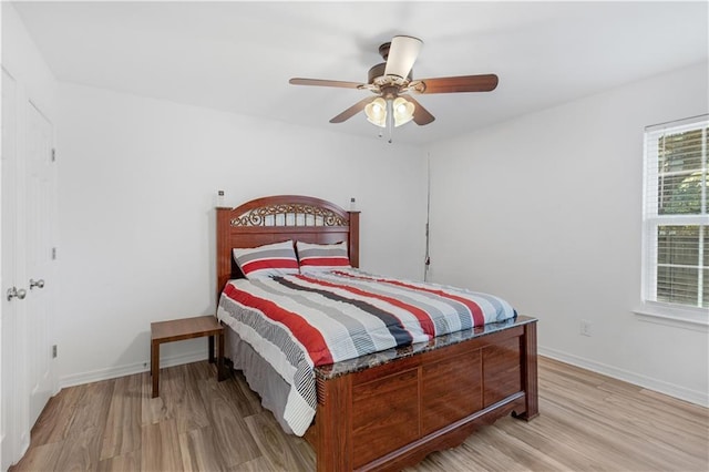 bedroom featuring light wood-style flooring, baseboards, and a ceiling fan