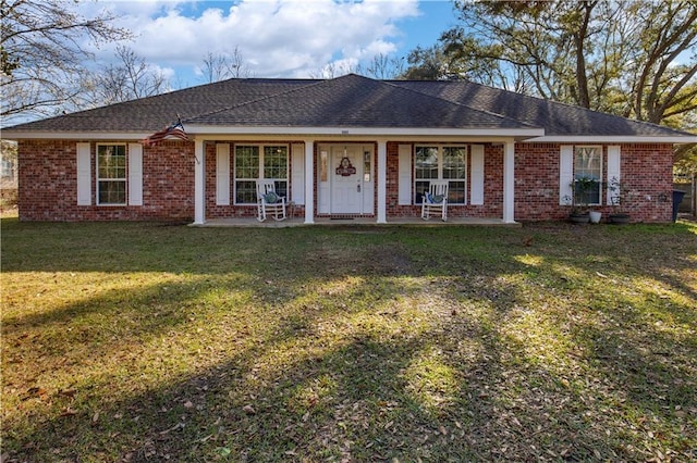 single story home featuring brick siding, a porch, a front yard, and a shingled roof