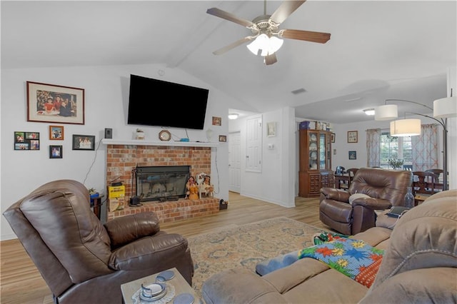 living area featuring a fireplace, vaulted ceiling with beams, visible vents, a ceiling fan, and wood finished floors