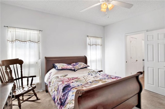 carpeted bedroom featuring ceiling fan and a textured ceiling