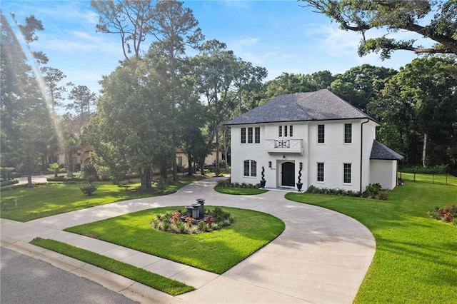 colonial inspired home with a balcony and a front lawn