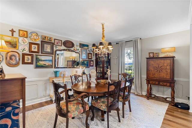 dining area with hardwood / wood-style floors, ornamental molding, and a chandelier