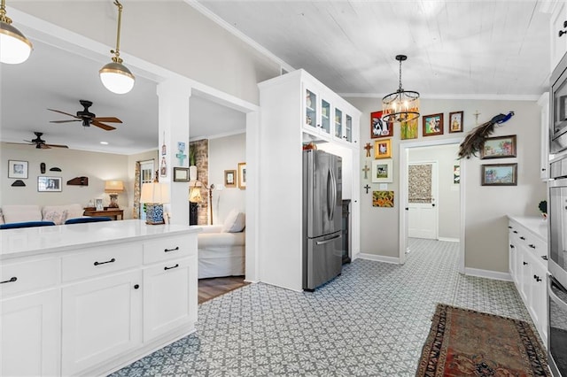 kitchen with stainless steel fridge, white cabinets, hanging light fixtures, and ornamental molding